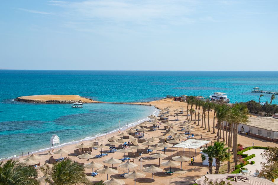 Idyllic beach scene with rows of umbrellas and azure ocean, perfect for travel and relaxation themes.